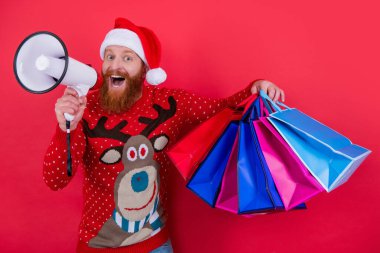 Sakallı adam elinde alışveriş torbalarıyla megafona bağırıyor. Noel Baba Noel indirimi duyurusu yapıyor. Tatil indirimi duyurusu. Dükkan duyurusu. Mutlu Noeller..