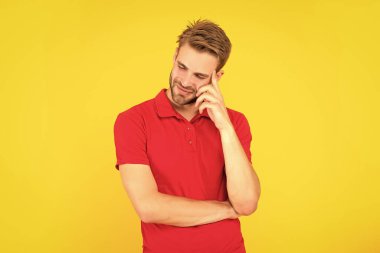 Sarı arka planda, kırmızı gömlekli neşeli, traşsız genç adam..