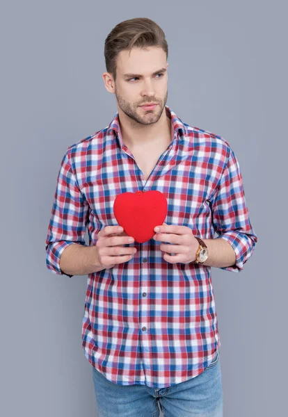 studio shot of young man with heart gift. valentines day and love. heart love gift of man for valentines day. man hold love heart gift isolated on grey background.