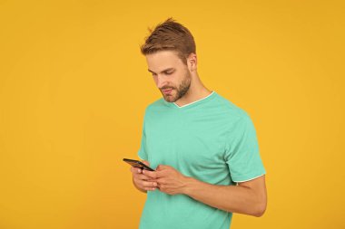 guy with bristle chatting on smartphone on yellow background, technology.