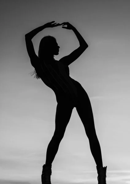 Woman ballet dancer shadow figure silhouetted on evening sky, silhouette.
