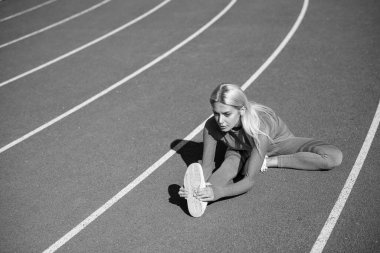 Spor ve spor. Sağlıklı bir yaşam tarzı. Açık hava stadyumunda antrenman. Beden eğitimi. Atletik bayanın esnek bir vücudu var. Esneme. Enerjik kadın ısınıyor. Spor kıyafetli kız ısınıyor..