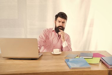 Ofis masasında oturmayı düşünen ciddi bir adam. Ofis işi.