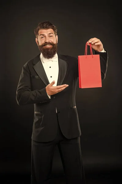黒を基調としたタキシードの弓のネクタイ姿の幸せな男が買い物袋にビジネス報酬を提示します ごあいさつだ コピースペース — ストック写真