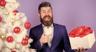 Meslektaşlarım için en iyi hediyeler. Ofis noel partisi. Adam sakallı hippi resmi takımı Noel ağacının yanında. Noel hediyeleri ve dekorasyonlar. Gizli Noel Baba konsepti. Kış tatili Noel selamları.