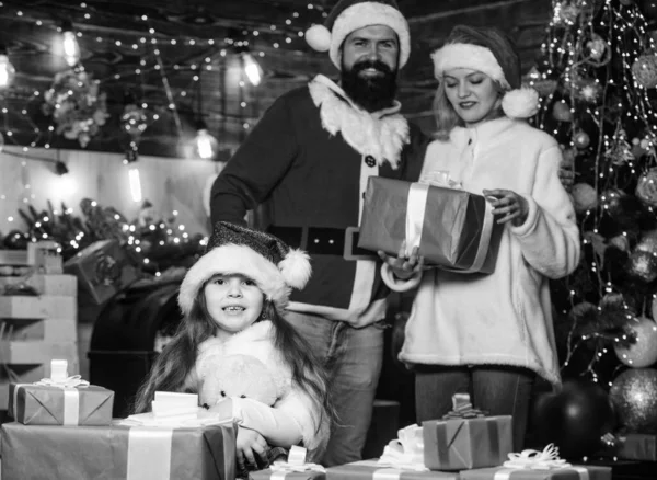 中に何が サンタ ハットの小さな子供と両親 クリスマスプレゼント箱 プレゼントを開けなさい 冬休みだ 買い物の販売 幸せな家族は新年を祝う メリー クリスマス — ストック写真