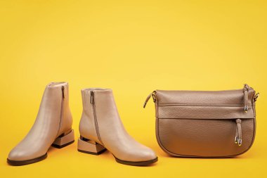 stylish leather boots and hat on yellow background with copy space, accessories.