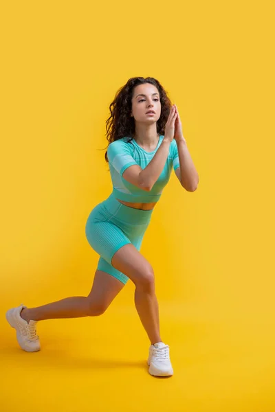 sport woman do lunge exercise at studio. sport woman doing lunge exercise isolated on yellow background. sport lunge exercise.