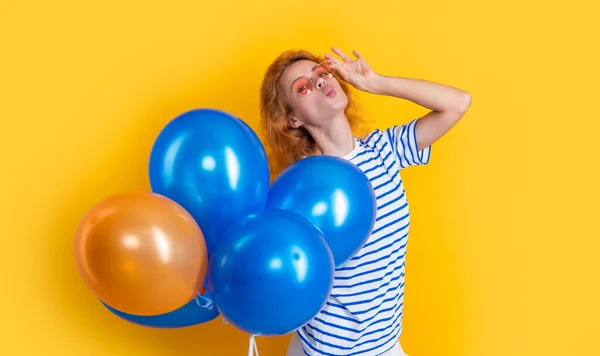 party girl with balloon in sunglasses. smiling girl hold party balloons in studio. girl with balloon for party isolated on yellow background.