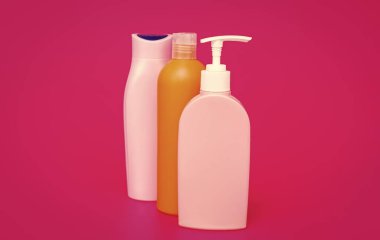 Multicolor plastic liquid containers for cosmetic products packaging in row pink background copy space, bottles.