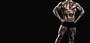 Vücut geliştiren kaslı vücut geliştirici pozu. Vücut geliştirmedeki vücut geliştirici siyah arka planda yalnız poz veriyor. Vücut geliştirme pankartıyla kaslı vücut geliştirici. Vücut geliştiricisinin stüdyo çekimi.