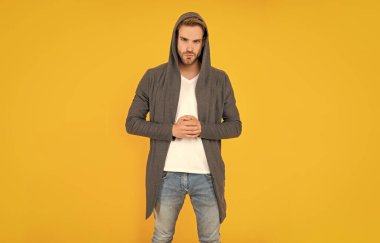 Kendine güvenen ve yakışıklı, tıraşsız adam. Erkek modası. Erkek güzelliği. Tüylü adam. Sarı arka planda sakallı genç bir adam. saç ve sakal bakımı.
