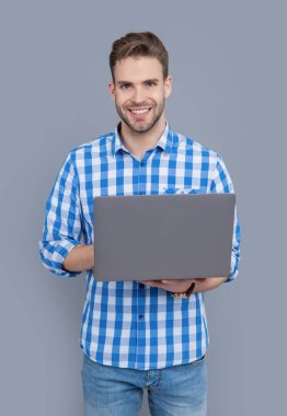 Üniversite öğrencisi online çalışmak için dizüstü bilgisayar kullanıyor. Dizüstü bilgisayar yazan mutlu bir adam. Online eğitim. Lise eğitimi.