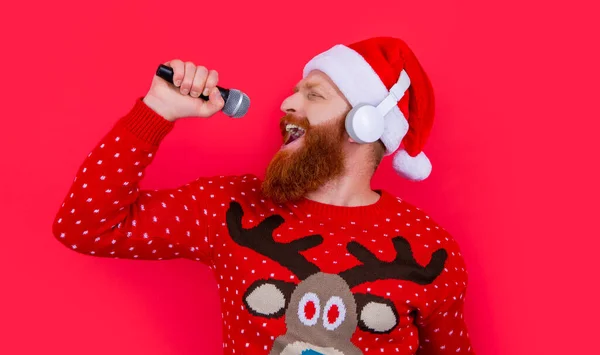 christmas karaoke music. cheerful man singing christmas music in karaoke. christmas santa man singing karaoke music isolated on red background.