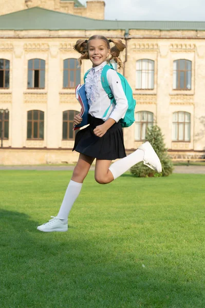 穿着校服的快乐少女在半空中跳跃 精力充沛的女学生背着书包 回学校去 — 图库照片