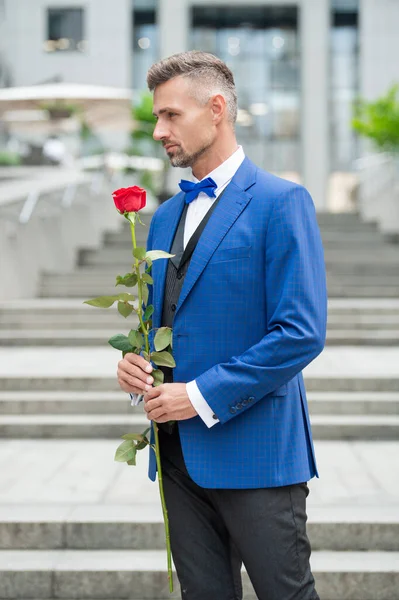 elegant man in tuxedo at romantic occasion. man with romantic present. handsome romantic man hold rose.