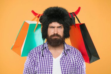 Wild about shopping. Shopping concept. Guy shopping sales season with discounts. Full packages of items. Man strict face wear hat of bull with horns. Hipster shopping addicted or shopaholic. clipart