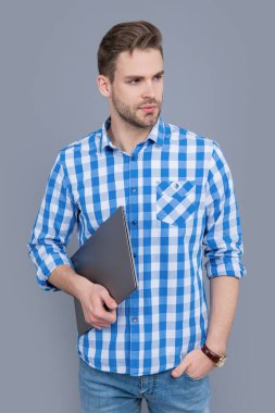 Dizüstü bilgisayarı tutan ciddi bir adam. Dizüstü bilgisayarı olan serbest çalışan biri. Dizüstü bilgisayar kullanıcı stüdyosu gri renkte izole edildi.