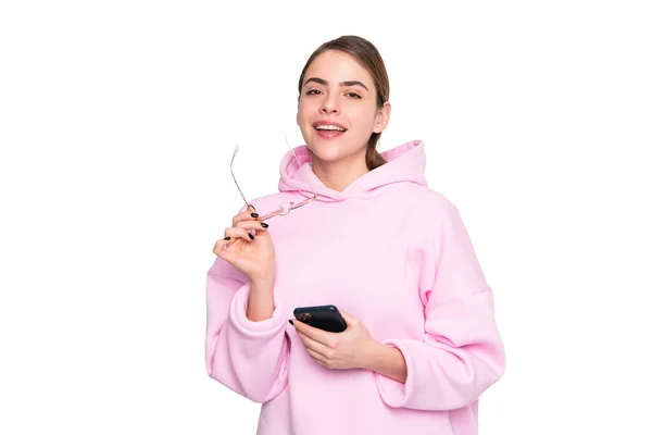 快乐的年轻女性 身穿宽松的粉色帽衫 手持眼镜和手机 与白色手机隔绝在一起 — 图库照片