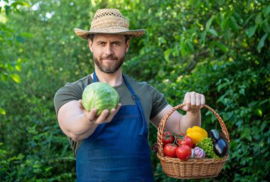 Hasır şapka sepeti dolusu sebze taşıyan adam. seçici odak.