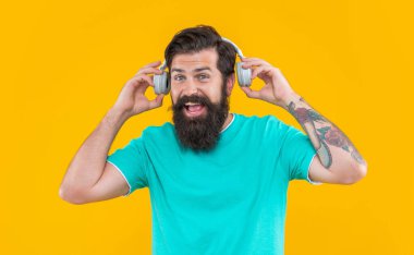 Müzik dinliyordum. Modern mutlu adam cihazı. Hipster adam sarı kulaklıkla müzik dinliyor. Hippi kulaklıklı adam müzik dinliyor. Kulaklıklı hipster adamın stüdyo fotoğrafı..