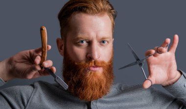 Berber adam kuaförde makas ve bıçak tutuyor. Berber dükkanı konsepti. Berber Gri Stüdyo 'da izole edilmiş. Berber dükkanında elinde makas olan bir adam. Berber dükkanındaki berber..