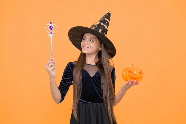 happy witch kid with magic wand and pumpkin jack o lantern wear costume of wizard on halloween party, halloween miracle play.