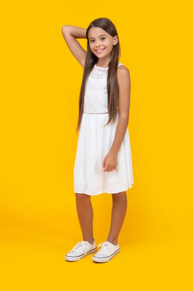 正のティーン女の子で白いドレスに立って黄色の背景 — ストック写真