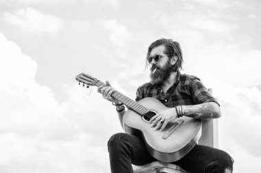 Müziğe benziyor. Uzun saçlı hippi ve bıyıklı gitarist. Müzik aleti olan erkek gitarist. Country müzik konsepti. Sakallı adam akustik gitar çalar. Sıradan bir adam insani duygularını ifade eder..