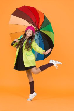 İyi eğlenceler. Pozitiflik kavramı. Yağmurlu gün eğlencesi. Şemsiyenin altında mutlu bir yürüyüş. Yağmur konseptinin tadını çıkarın. Çocuk kız mutlu renkli gökkuşağı şemsiye tutun. Uygun giysiler ile yağmurlu hava. Parlak şemsiye.