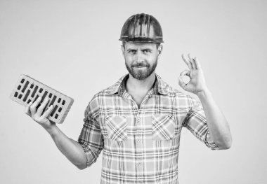 Profesyonel duvar ustası iyi bir jest yaptı. İnşaat mühendisi. İşçi ya da işçi günü. Tuğlalı bir işçi. Adam işçi üniforması giyiyor. Kasklı yakışıklı bir müteahhit. Olgun adam kareli gömlek giyer..