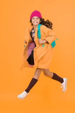 Havada yürümek. Sarı arka planda okula koşuşturan küçük bir çocuk. Mutlu kız aktif yaşam tarzını seviyor. Küçük okul çocuğu sonbaharda aktif hisseder. Etkin ve enerjik.