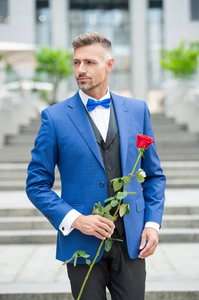 elegant man in tux at romantic occasion. man with romantic present. handsome romantic man with rose.