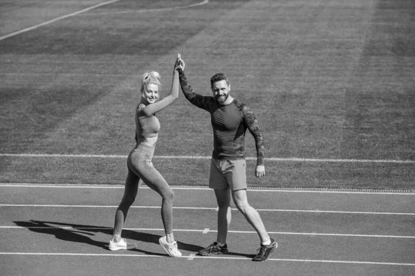 Sport success. male and female coach on stadium running track arena. healthy lifestyle. sport couple celebrate team win. fitness partners. athletic man and sexy woman compete in armwrestling.
