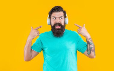 Hippi kulaklıklı adam müzik dinliyor. Kulaklıklı hipster adamın stüdyo fotoğrafı. Müzik dinliyordum. Modern erkek aleti. Kulaklıkla müzik dinleyen hippi adam sarıda izole edilmiş..