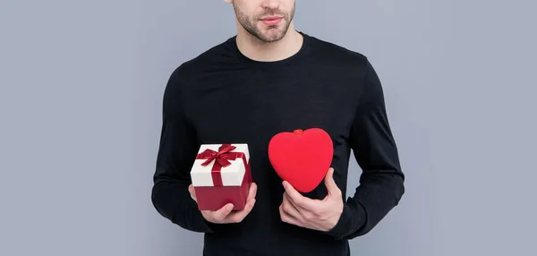 cropped view of man with valentine present in studio. valentine present for man. box of valentine present. man hold valentine present isolated on grey background.