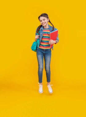 Sarı arka plandan atlayan mutlu kız, okul. Havada enerjik genç kız. Okul eğitimi. Okula geri dön..