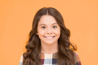 Çocuğu mutlu eden eğitim. Sarı arka plandaki mutlu küçük kız. Uzun esmer saçlı küçük çocuk gülümsemesi. Mutlu bir çocukluk. Okul zamanı..