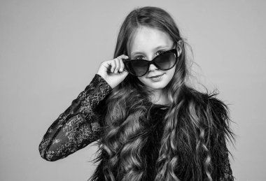 Moda gözlüğü takan şık bir çocuk. Mevsimlik sonbahar modası. Güneş gözlüklü genç kız. Mutlu çocukluk. Güzellik ve moda. Havalı olmak. Çocuğun uzun kıvırcık saç stili var. Boşluğu kopyala.