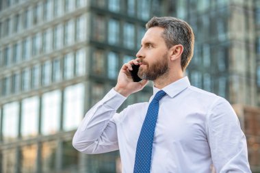 Patron akıllı telefon konuşması yapıyor. Patronun akıllı telefon konuşması. Akıllı telefonlu patron konuşuyor. Akıllı telefonlu patronun iş görüşmesi..