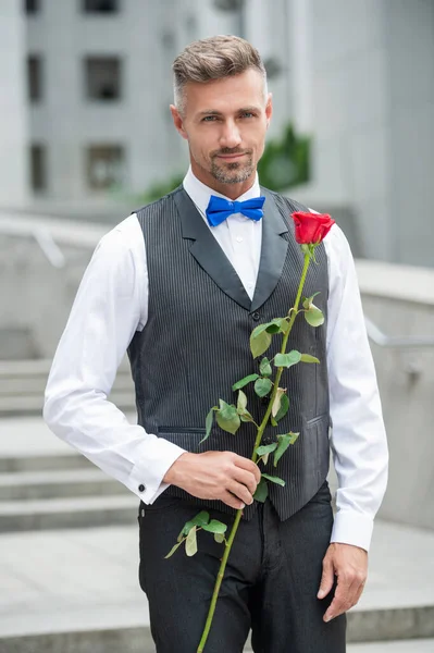 爱日的概念 黄褐色燕尾服的男人带着爱情玫瑰 情人节送花礼物 — 图库照片