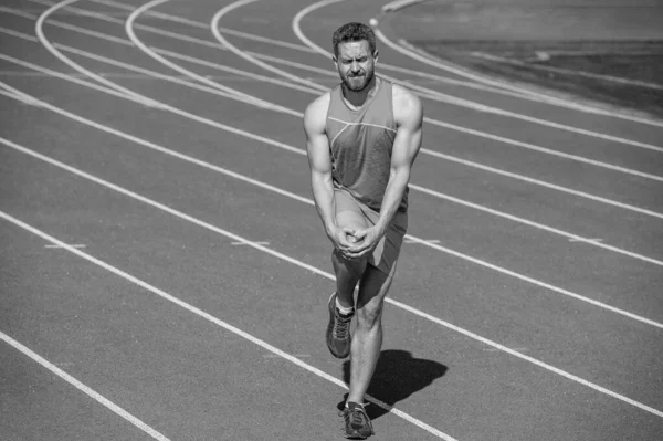 Erkek koşucu spor sonrası travma ve spor sakatlığı nedeniyle kaslarını esnetir..