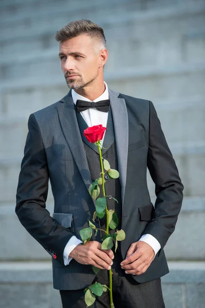 special occasion concept. elegant man with rose for special occasion. tux man outdoor at special occasion.