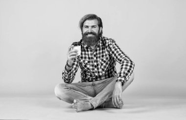 Beyaz bardak tutan yakışıklı sakallı adam. Bardakla içecek. Çay ya da kahve içmek. Günaydın. Evde sabah havası var. İlham konsepti. Hipster adam kahve içer. Yeni çay fincanı zamanı..