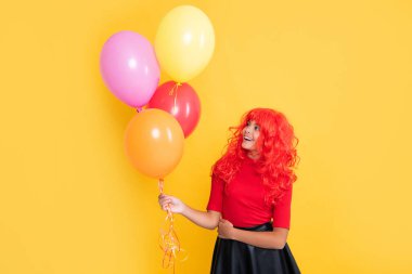 Sarı arka planda parti balonu olan mutlu çocuk..