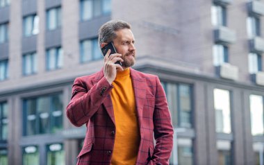Akıllı telefon iş iletişimi. Akıllı telefonlu bir iş adamı. Yakışıklı iş adamı akıllı telefondan konuşur. İş adamı açık havada akıllı telefondan konuşur..