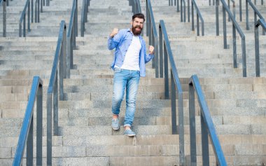 Bağıran hipster aşağıda yürüyor. Sakallı bir hippi. Merdivenlerde hippi bir adam var..