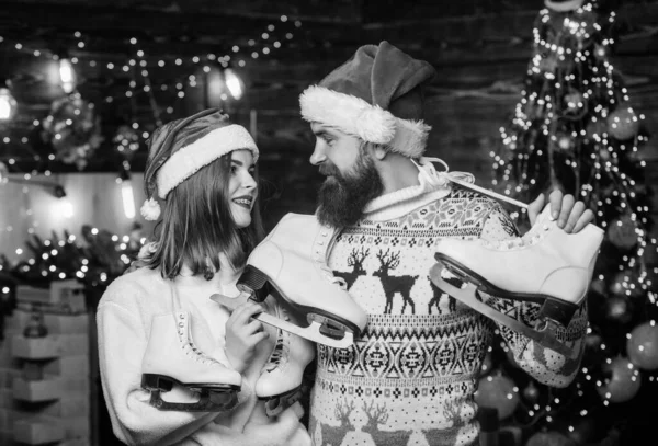 Winter sports. Equipment outdoor sport. Christmas gift. Winter holidays. Active winter. Happy couple with figure skates. Cheerful people with skates. Family leisure. Bearded man and Santa girl.