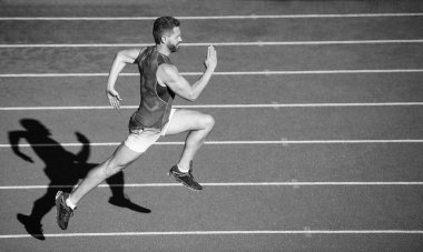 Enerjik atletik kaslı adam koşucu açık hava stadyumunda yarış pistinde koşuyor, acele et..