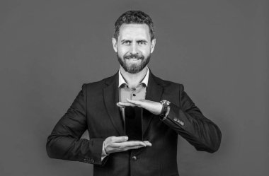 Telefon uygulaması reklamı. İş adamı ürünü sunuyor. Yeni akıllı telefonun sunumu. Video konferansı için mükemmel. Olgun gülümseyen adam cep telefonu ekranını gösteriyor. modern yaşam teknolojisi.